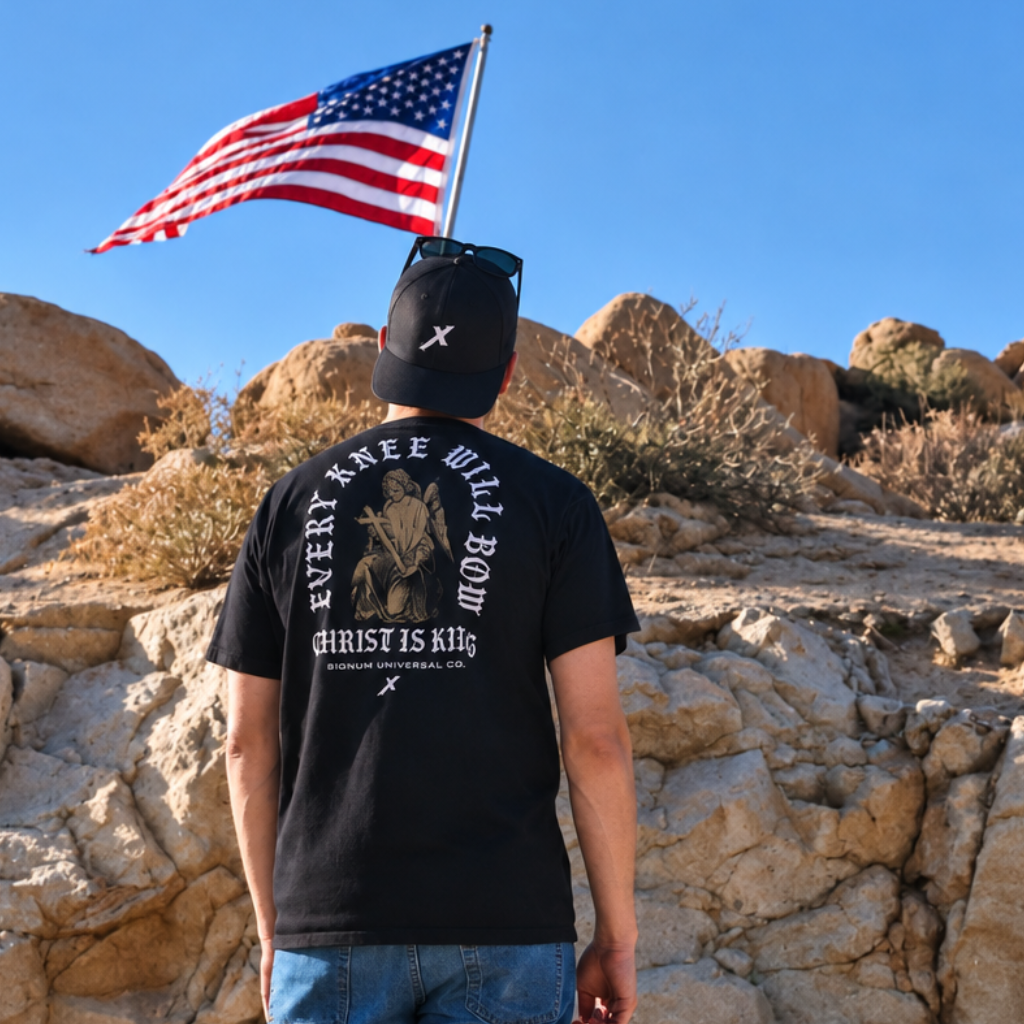 Man wearing Black Every Knee Will Bow Catholic Shirt, back print of angel at the cross. Model is 5'11" and wearing a Large