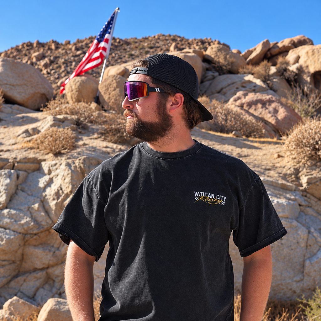 Man wearing washed black Vatican City Racing Catholic shirt, chest logo lifestyle. Model is 5'10" and wearing a Large