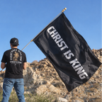 Man holding black Christ Is King Catholic flag outdoors, SIGNUMX lifestyle